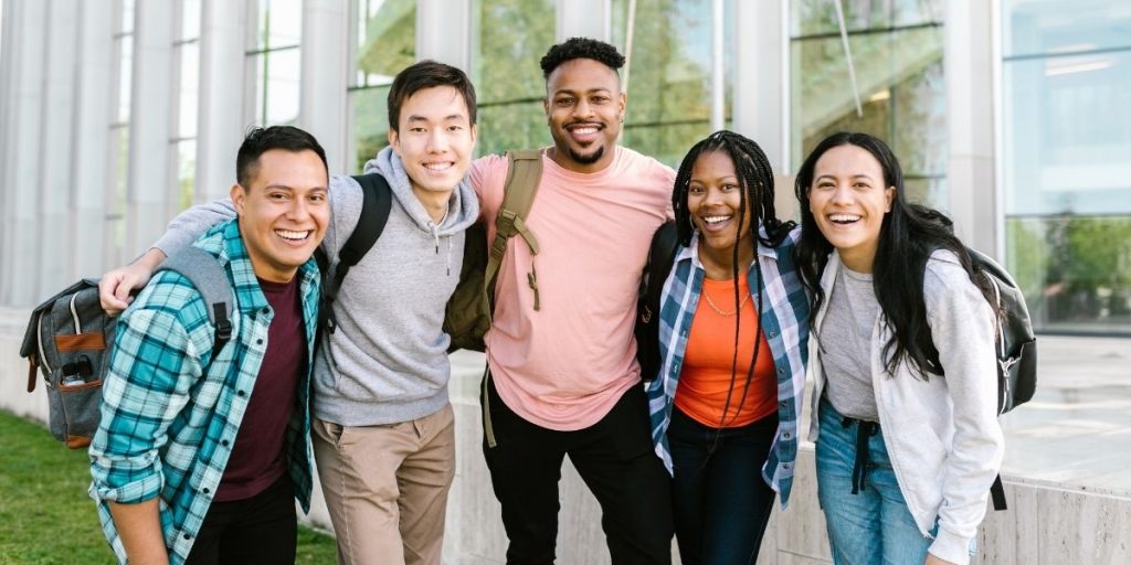 Vrolijke internationale studenten die samen naar de camera lachen